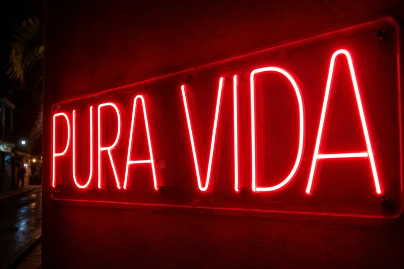 Red LED neon Pura Vida sign glowing on a dark exterior wall at night in Costa Rica